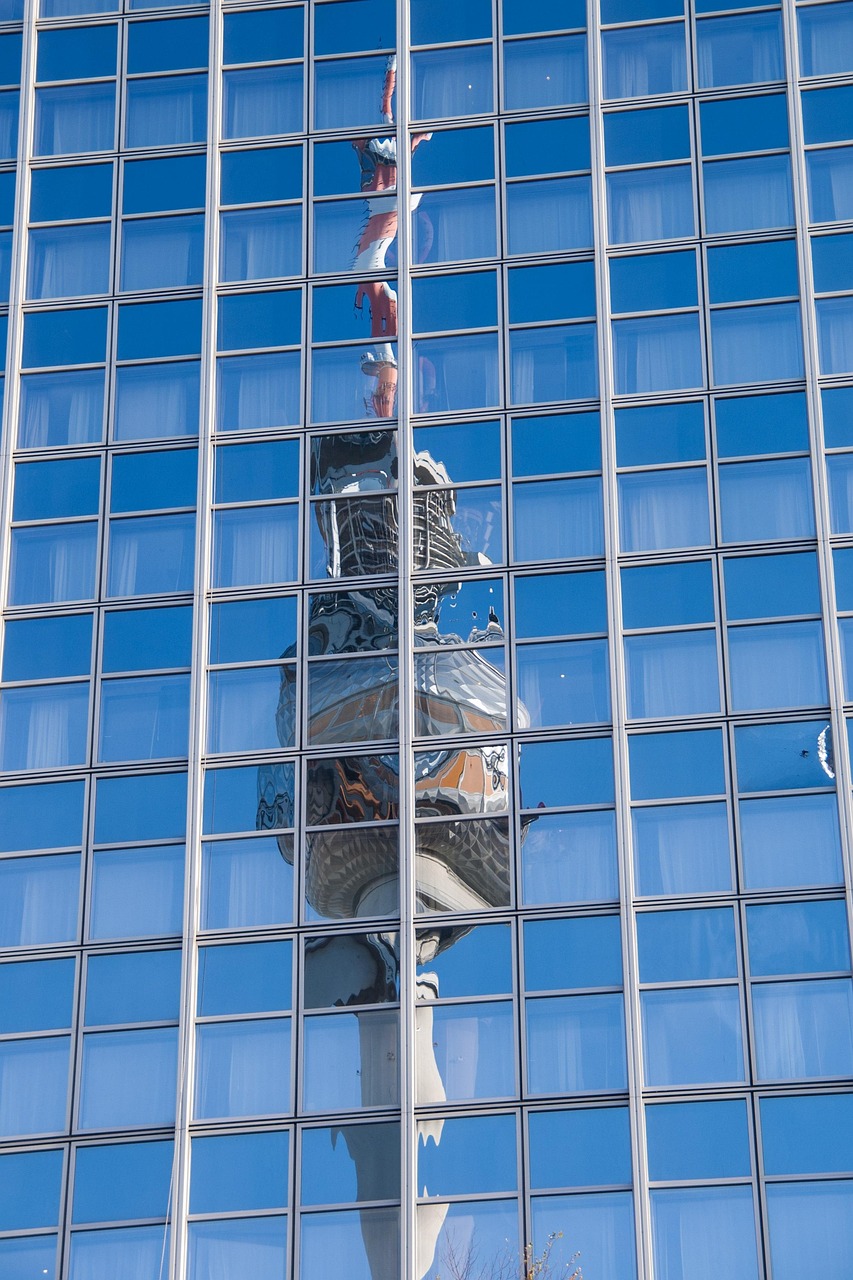 In einer Fassade aus Glasfenstern spiegelt sich der Berliner Fernsehturm als Symbol für die Menge an sanierungsbedürftigen Fenstern in Deutschland