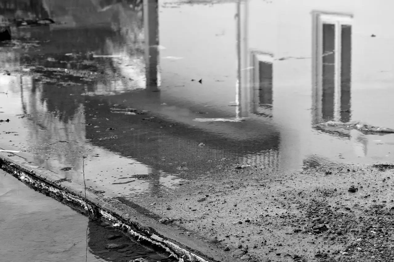 Ein altes, sanierungsbedürftiges Fenster spiegelt sich in einer Pfütze